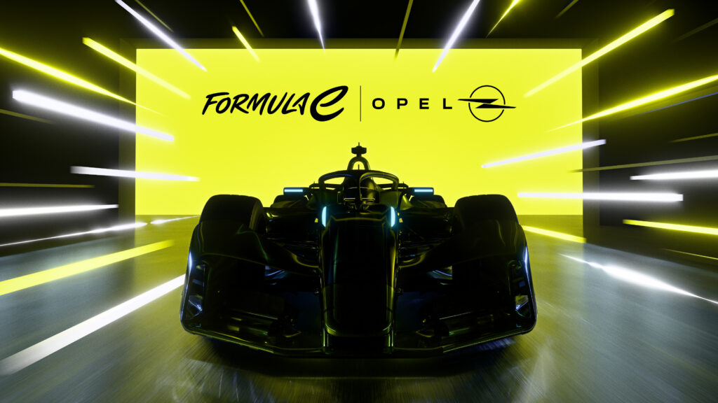 Frontansicht des Opel Formula E Gen4-Rennwagens in dunkler Lackierung, im Hintergrund eine leuchtend gelbe Wand mit den Logos von Formula E und Opel