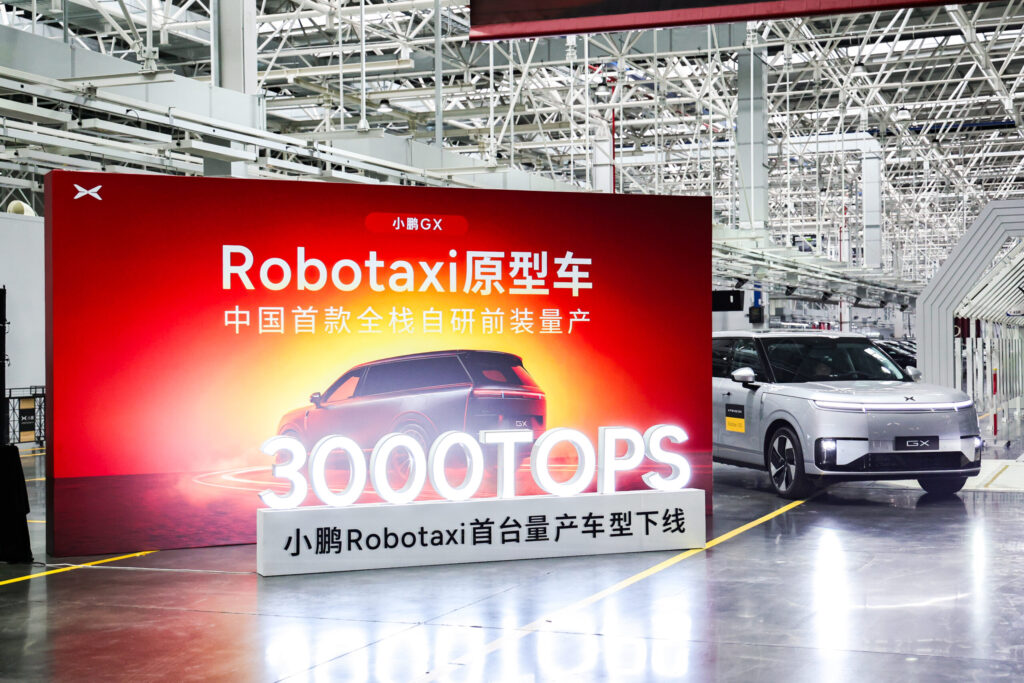 XPENG GX Robotaxi-Serienmodell in Produktionshalle neben roter Wand mit Aufschrift „3000TOPS"