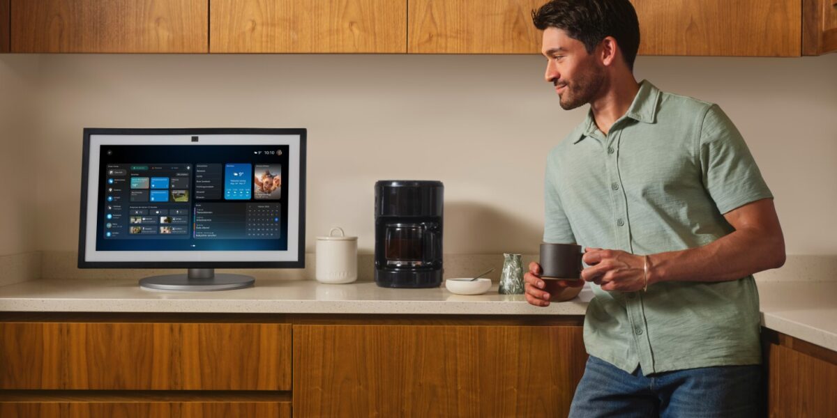 Mann in Küche blickt auf Amazon Echo Show mit Alexa+-Dashboard, Kaffeetasse in der Hand