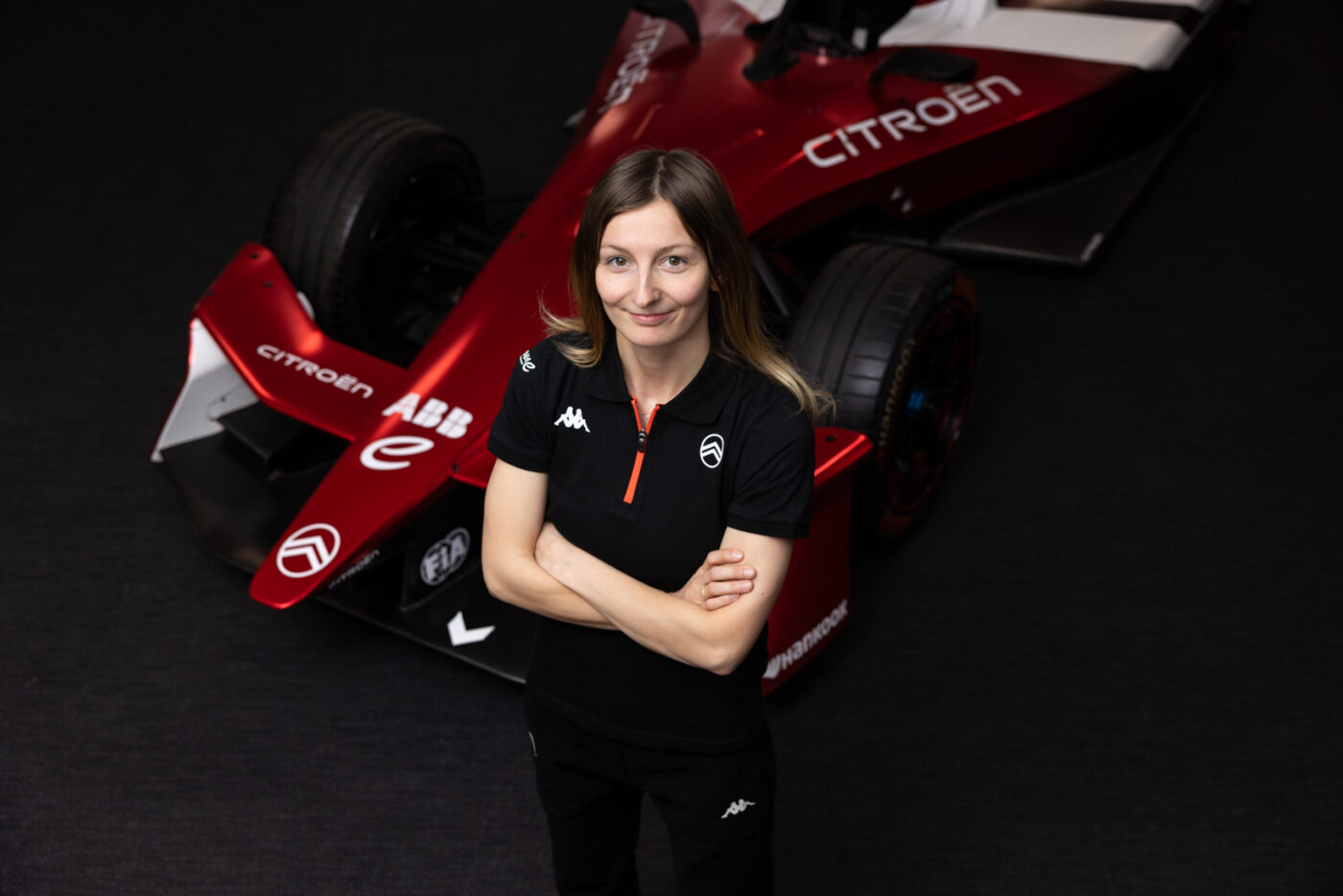 Doriane Pin in Citroën-Teamkleidung vor rotem Formel-E-GEN4-Fahrzeug im Studio