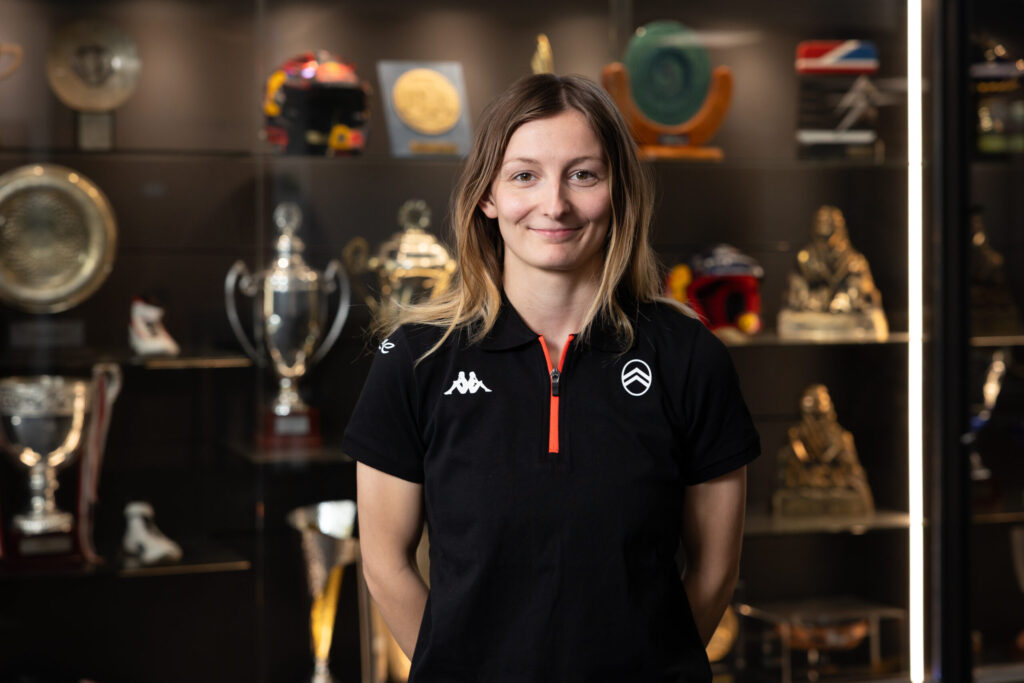 Doriane Pin in schwarzem Citroën-Racing-Polo vor Trophäenvitrine