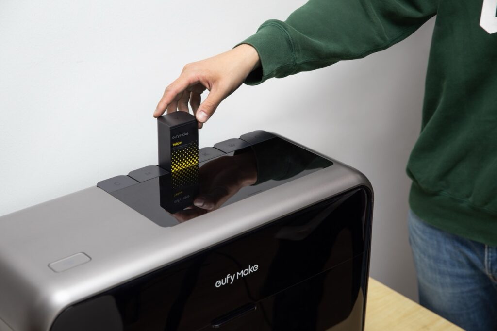 Hand setzt gelbe Tintenpatrone in den eufyMake E1 UV-Drucker ein