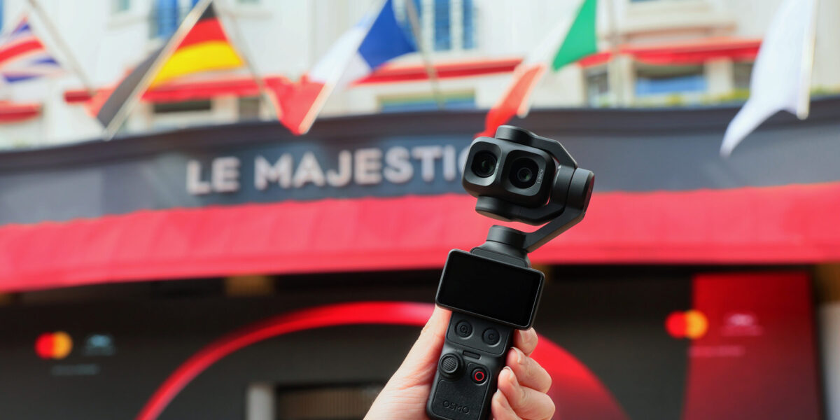 Hand hält DJI Osmo Pocket 4P mit Dual-Objektiv vor dem Hotel Le Majestic in Cannes