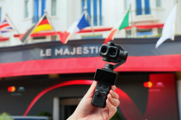 Hand hält DJI Osmo Pocket 4P mit Dual-Objektiv vor dem Hotel Le Majestic in Cannes