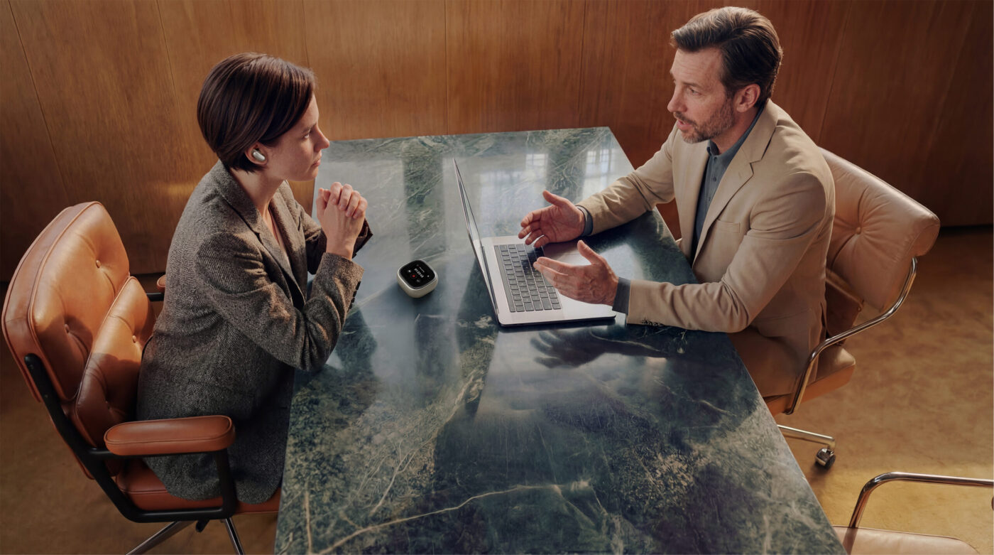 Frau mit soundcore Liberty 5 Pro Max im Ohr und Ladecase auf Marmortisch beim Business-Meeting
