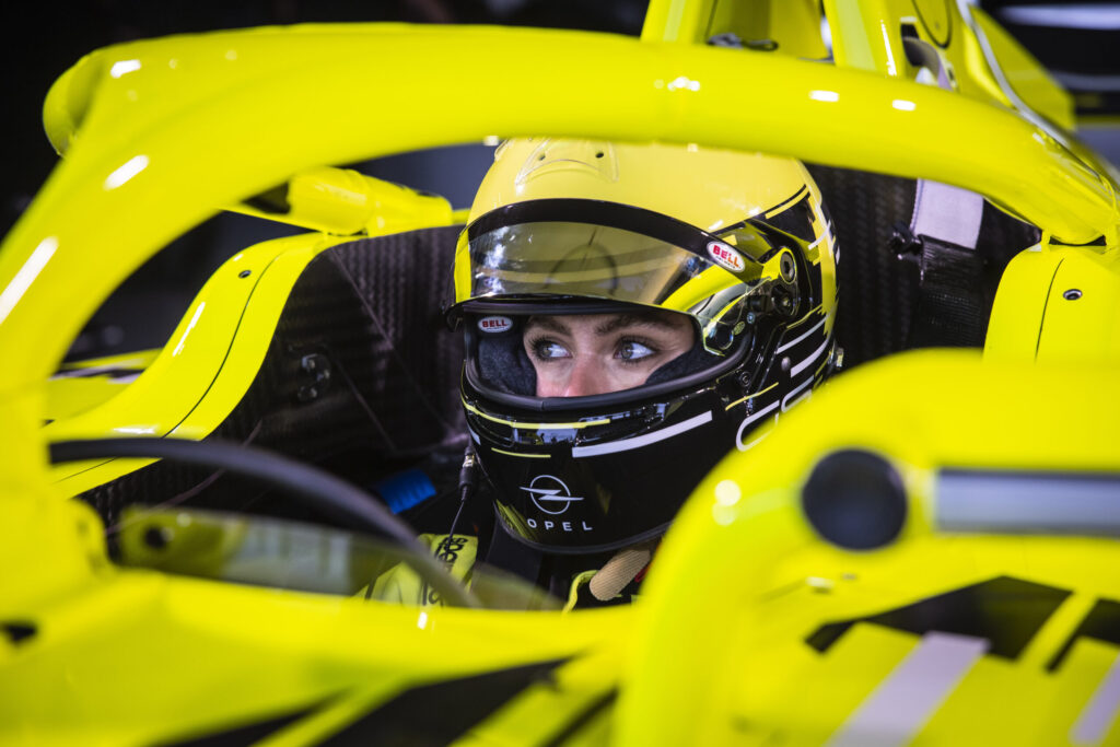 Sophia Flörsch mit Rennhelm im Cockpit des Gen 4 Formel E Fahrzeugs von Opel. 