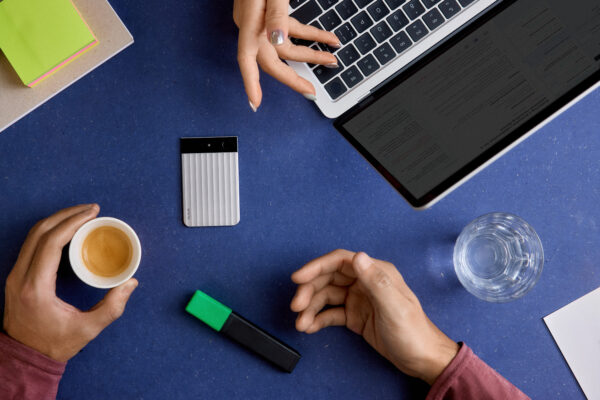 Plaud Note Diktiergerät auf blauem Schreibtisch neben MacBook, Espresso und Textmarker – Büro-Setting von oben