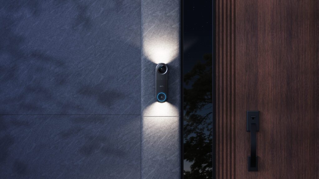 eufy Video Doorbell S4 mit aktiver Beleuchtung an Hauswand neben Holztür bei Nacht