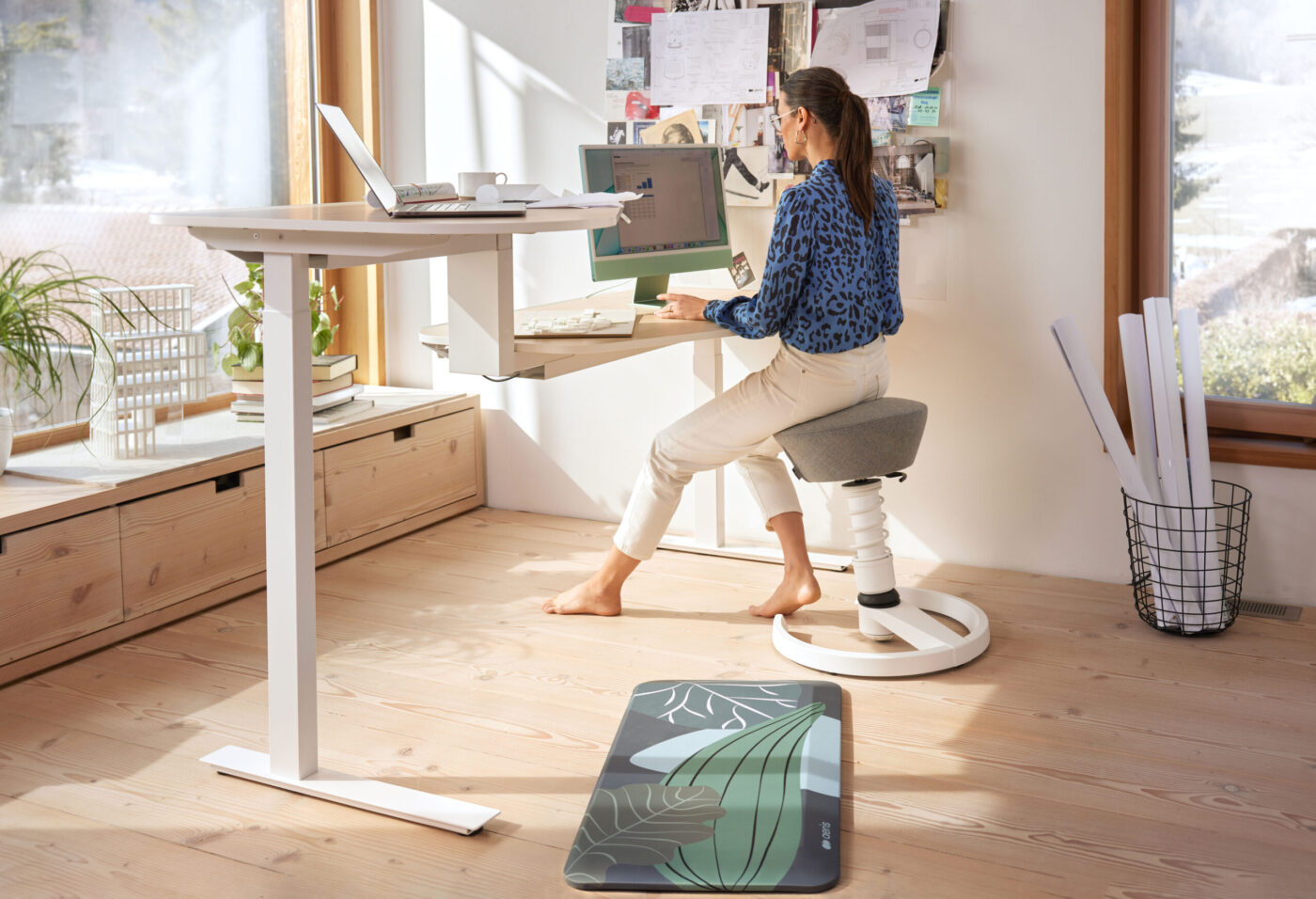 Frau arbeitet auf Aeris-Aktivhocker am höhenverstellbaren Schreibtisch im Home-Office