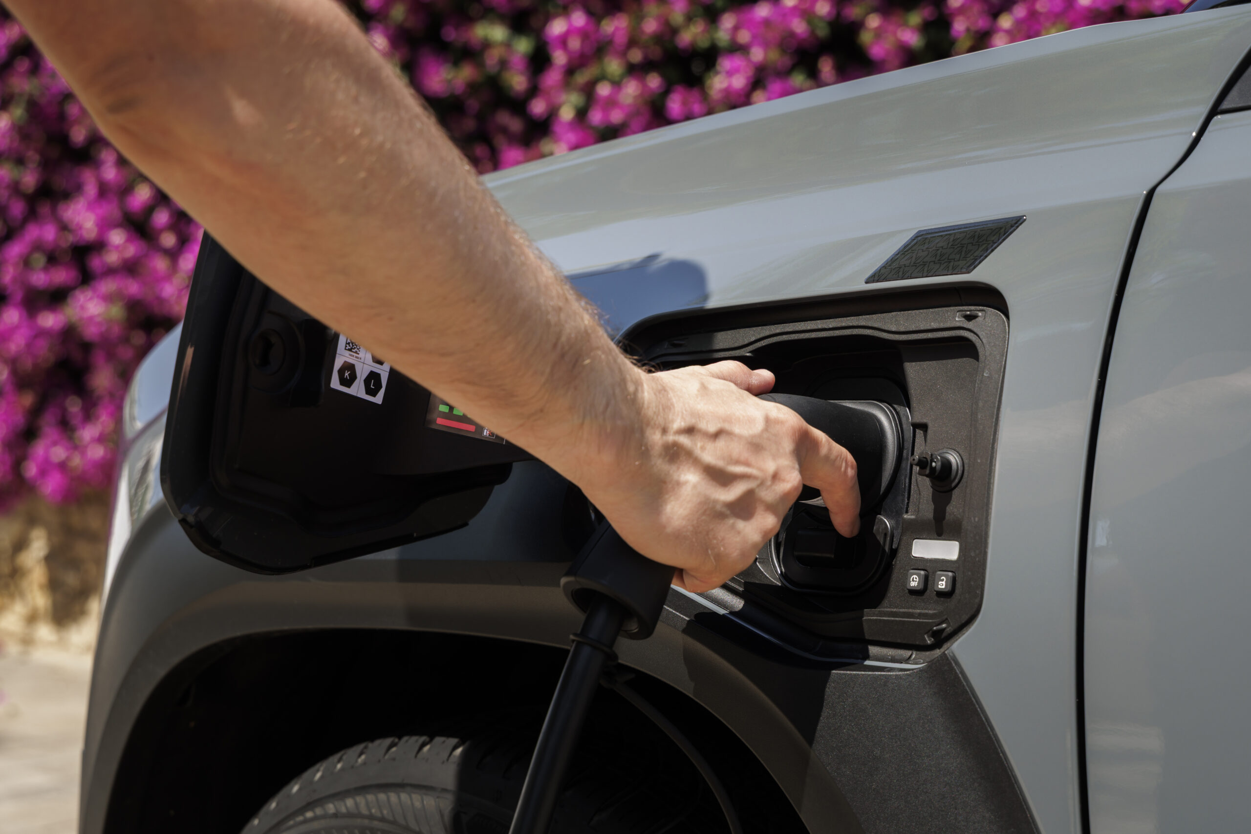 Hand steckt Ladekabel in die CCS-Ladebuchse des Renault 4 E-Tech in Hellgrau