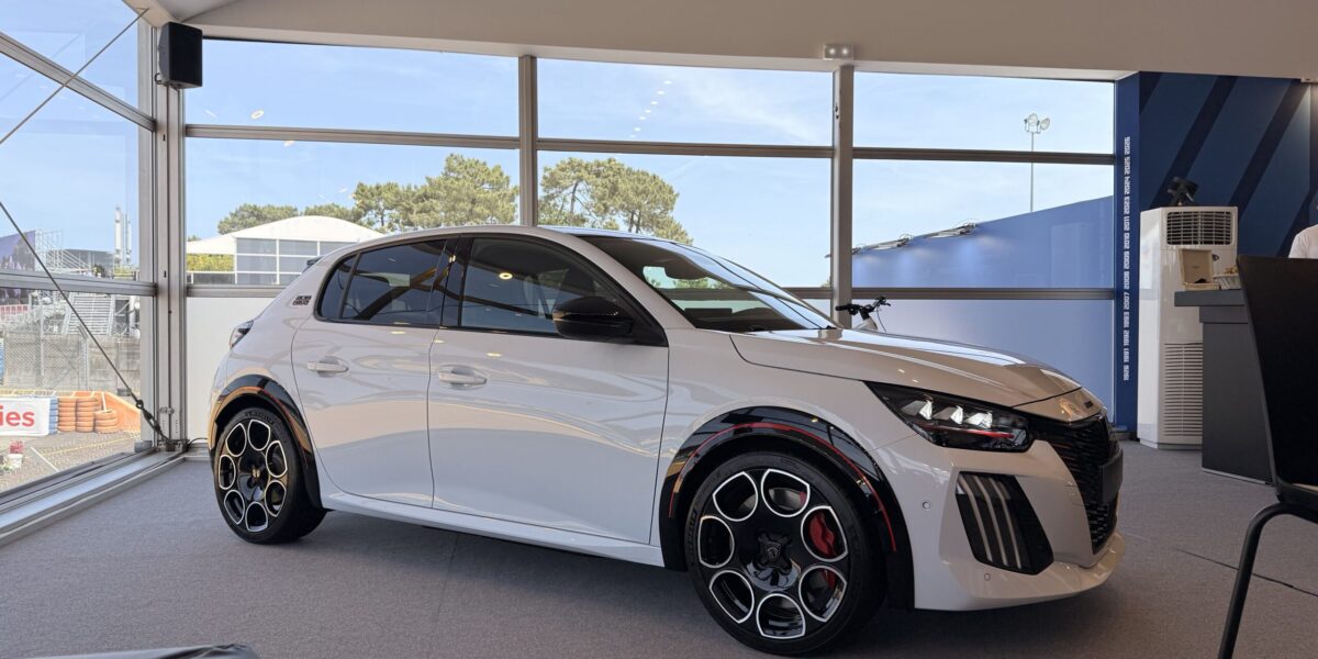 Peugeot E-208 GTi in Weiß im Ausstellungspavillon, Dreiviertelansicht mit roten Bremssätteln