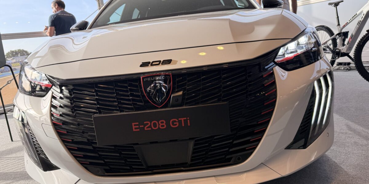Peugeot E-208 GTi in Weiß, Frontansicht mit schwarzem Grill und roten Akzenten auf Ausstellung
