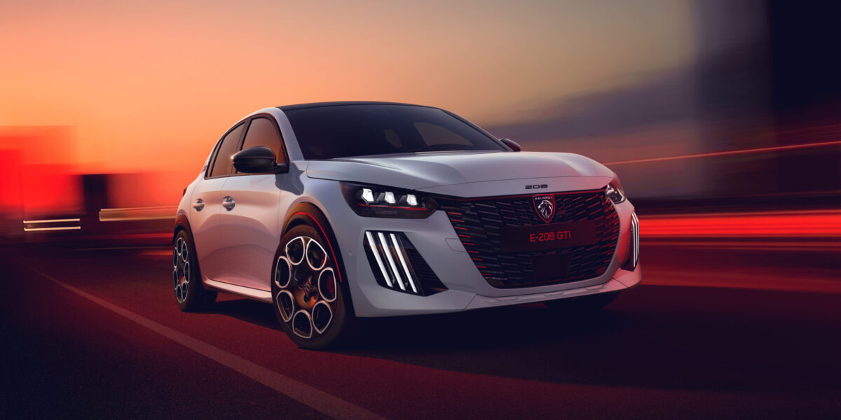 Peugeot E-208 GTi in Weiß fährt bei Sonnenuntergang auf einer Straße, Frontansicht