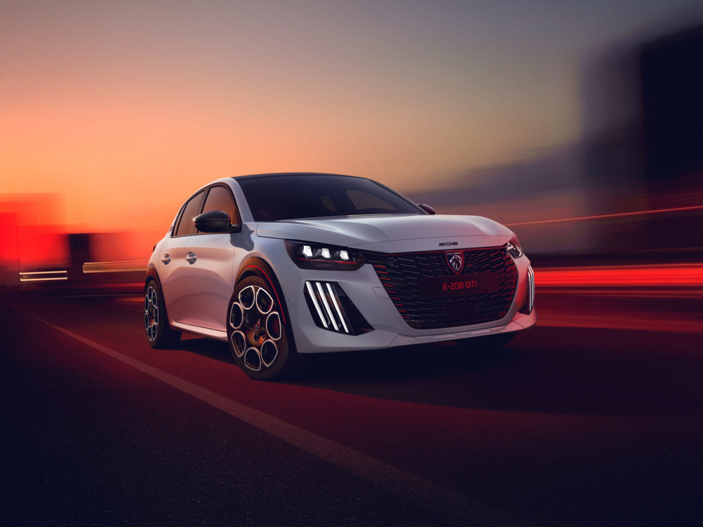 Peugeot E-208 GTi in Weiß fährt bei Sonnenuntergang auf einer Straße, Frontansicht