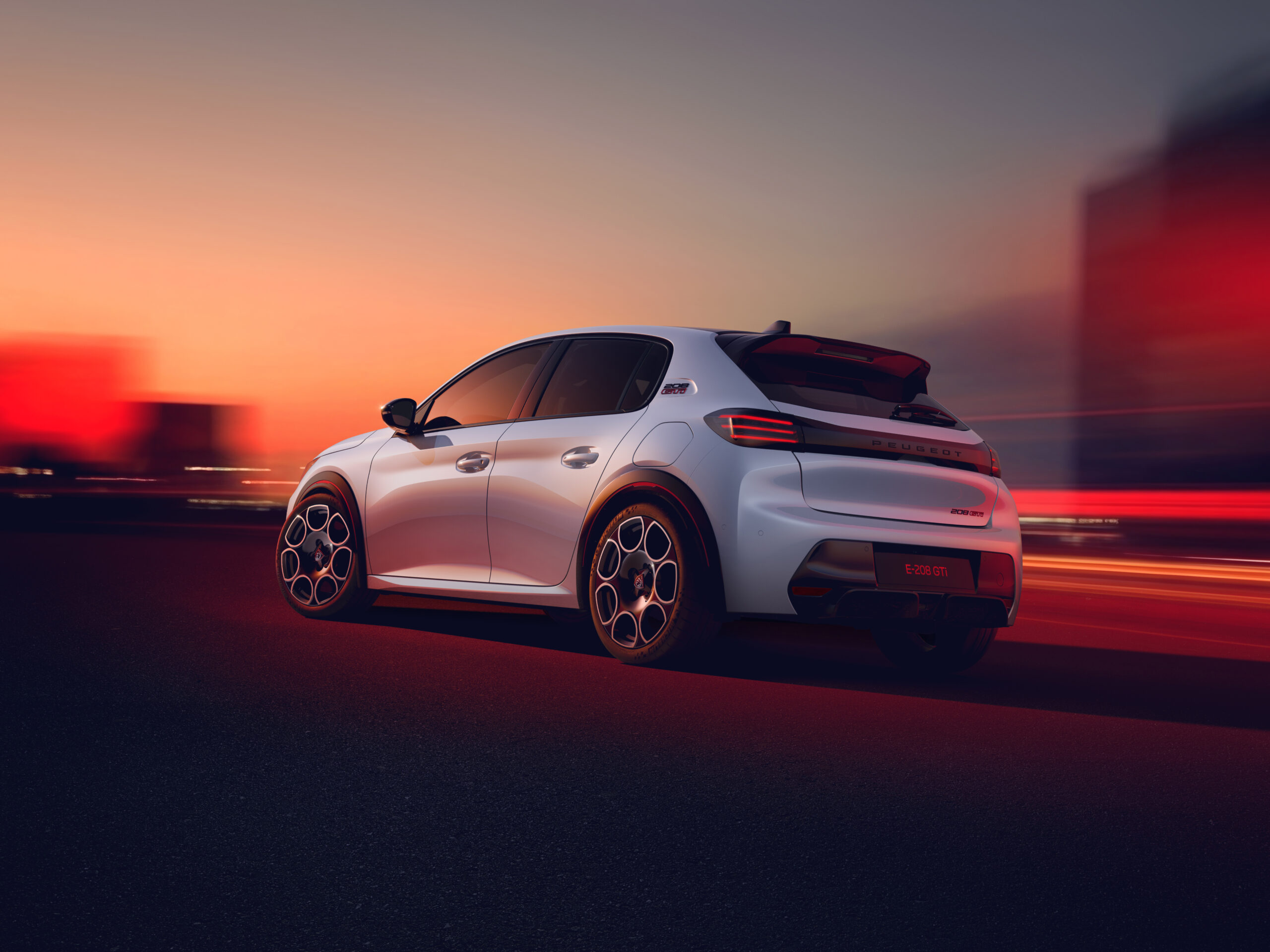 Peugeot E-208 GTi in Weiß von hinten auf nächtlicher Straße bei Sonnenuntergang