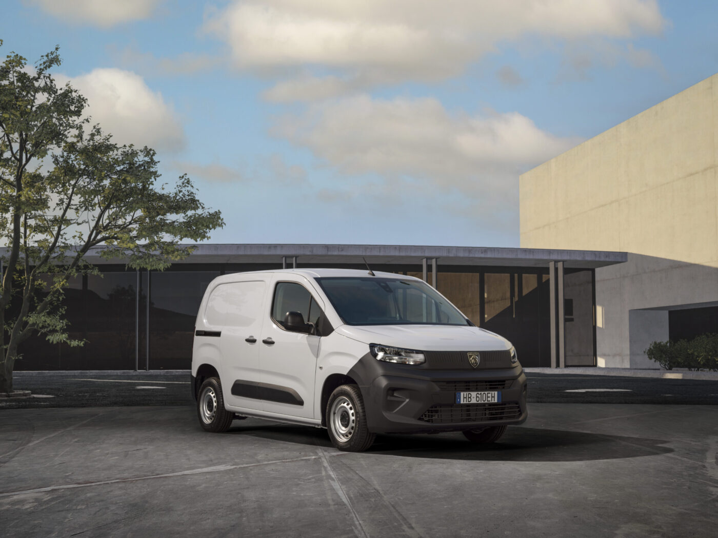 Peugeot Partner ACTIVE in Weiß, Frontansicht schräg links, parkend vor modernem Gebäude