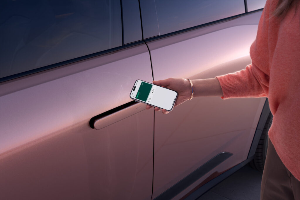 Hand hält Smartphone als digitalen Schlüssel an die Fahrertür des Škoda Peaq