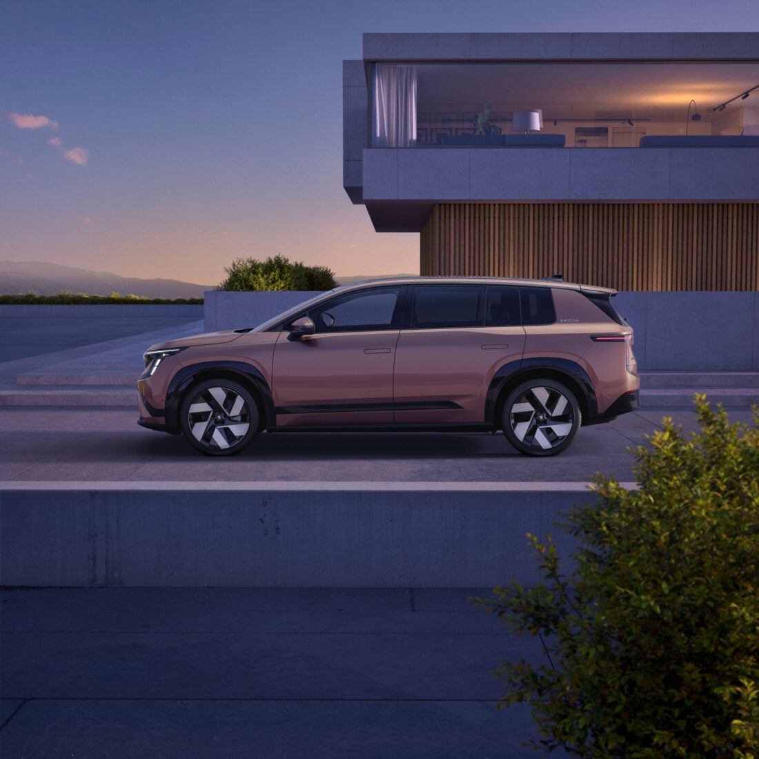 Škoda Peaq in Bronze-Metallic, Seitenansicht vor modernem Gebäude bei Abenddämmerung