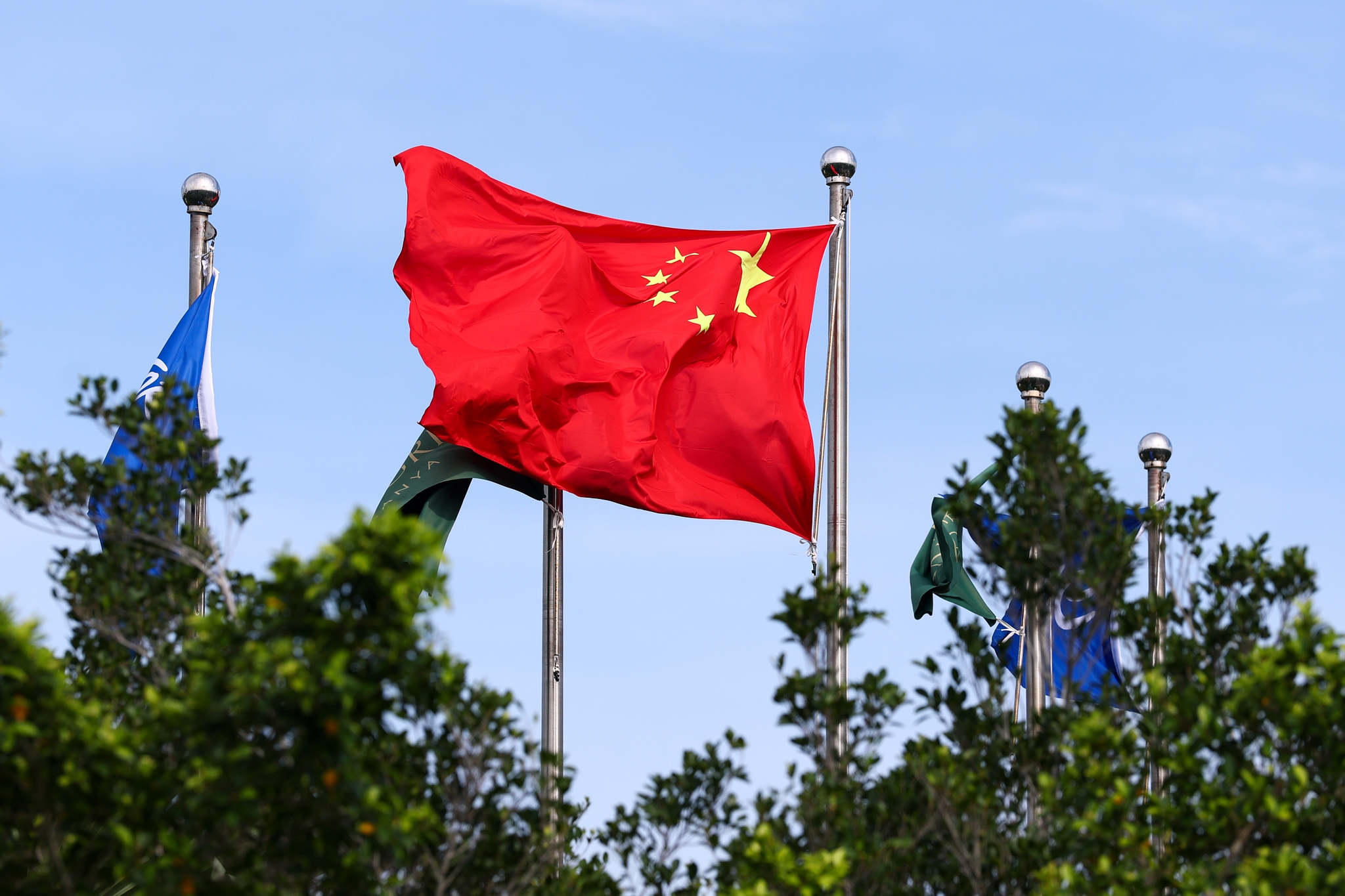 Chinesische Nationalflagge weht im Wind vor blauem Himmel in Sanya, China