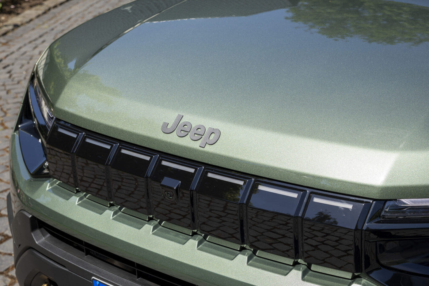 Jeep Avenger 2026 Frontgrill mit beleuchtetem Sieben-Schlitz-Design und Jeep-Schriftzug auf olivgrüner Motorhaube