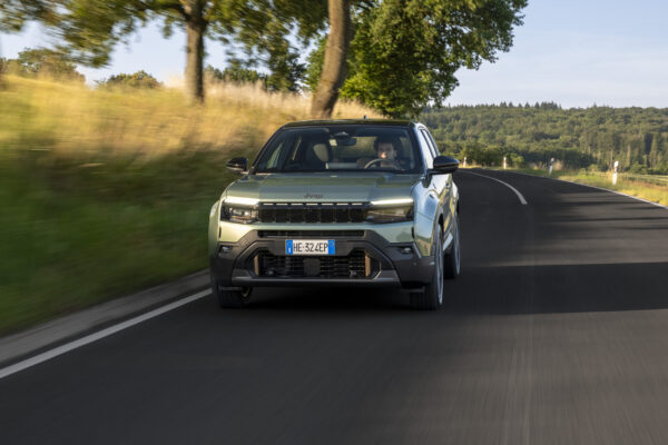 Jeep Avenger 2026 Facelift in Hellgrün-Metallic auf einer Landstraße, Frontansicht mit beleuchtetem Sieben-Schlitz-Grill