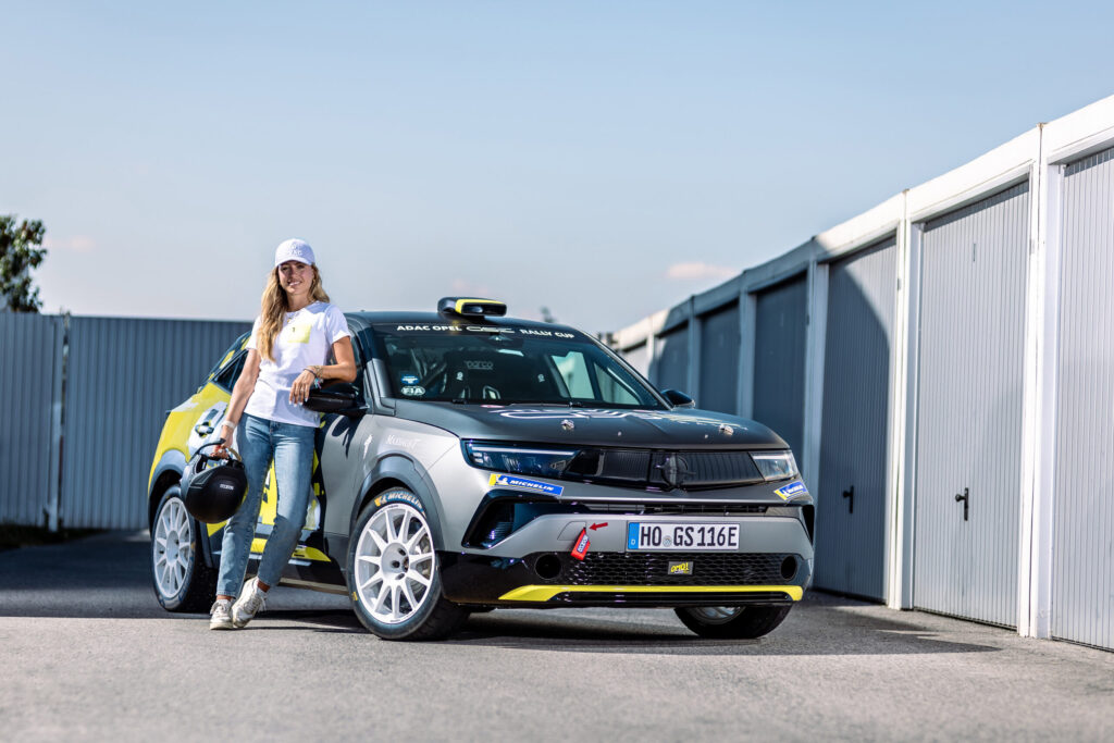 Sophia Flörsch mit Helm neben dem Opel Mokka GSE Rally im ADAC Opel GSE Rally Cup-Design