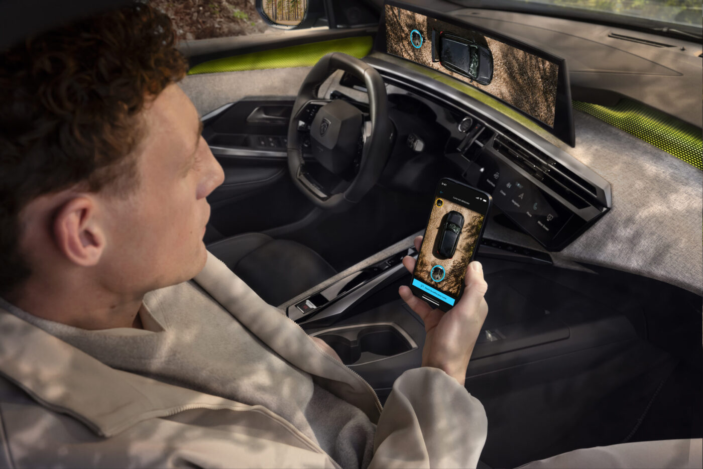 Beifahrer im Peugeot E-5008 Dog Edition nutzt Smartphone-App zur Hundeüberwachung per Dog-Guardian-Modus