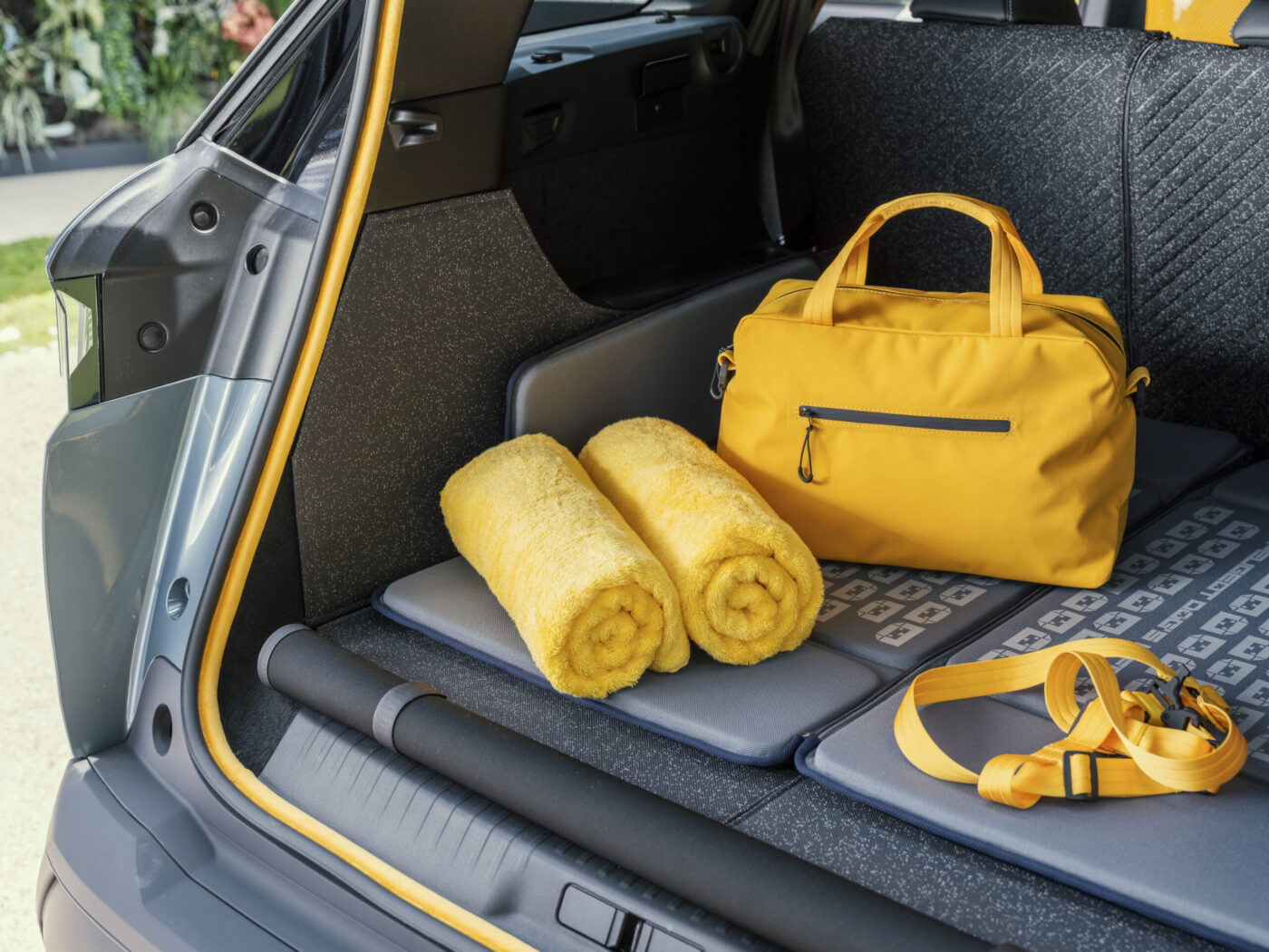 Kofferraum des PEUGEOT E-5008 Dog Edition Concept mit gelben Handtüchern, Tasche und Hundegeschirr