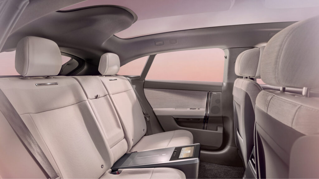 Range Rover GT Fondbereich mit heller Textilrücksitzbank, ausklappbarem Infotainment-Tray und minimalistischer Türverkleidung