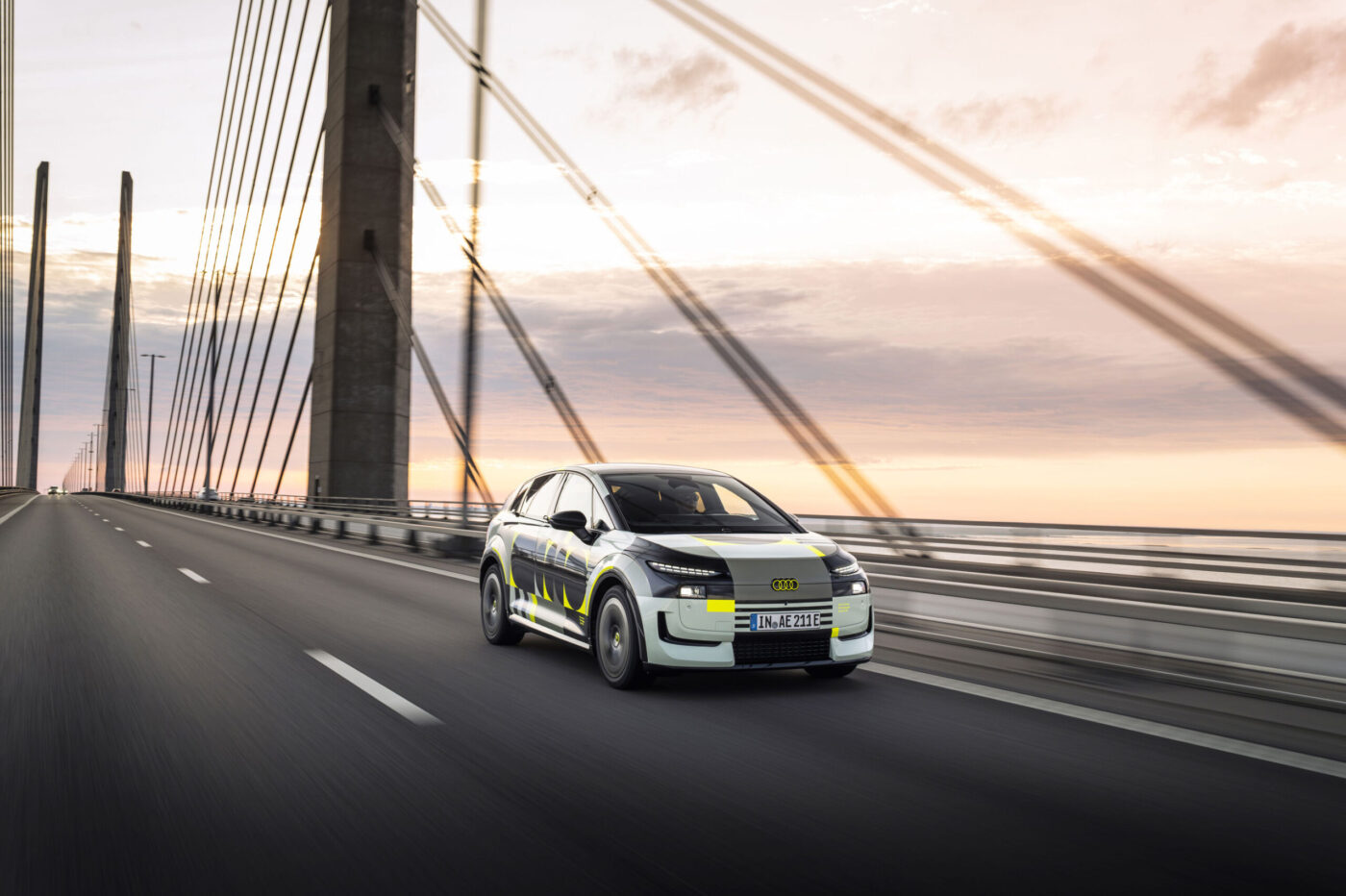 Audi A2 e-tron Prototyp mit Tarnfolie auf einer Hängebrücke bei Sonnenuntergang