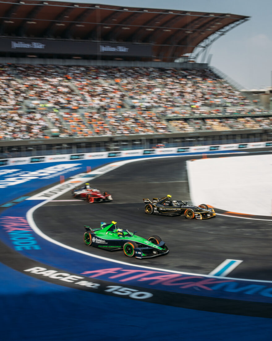 Drei Formel-E-Boliden in einer Kurve beim Rennen Nr. 150, vollbesetztes Stadion im Hintergrund