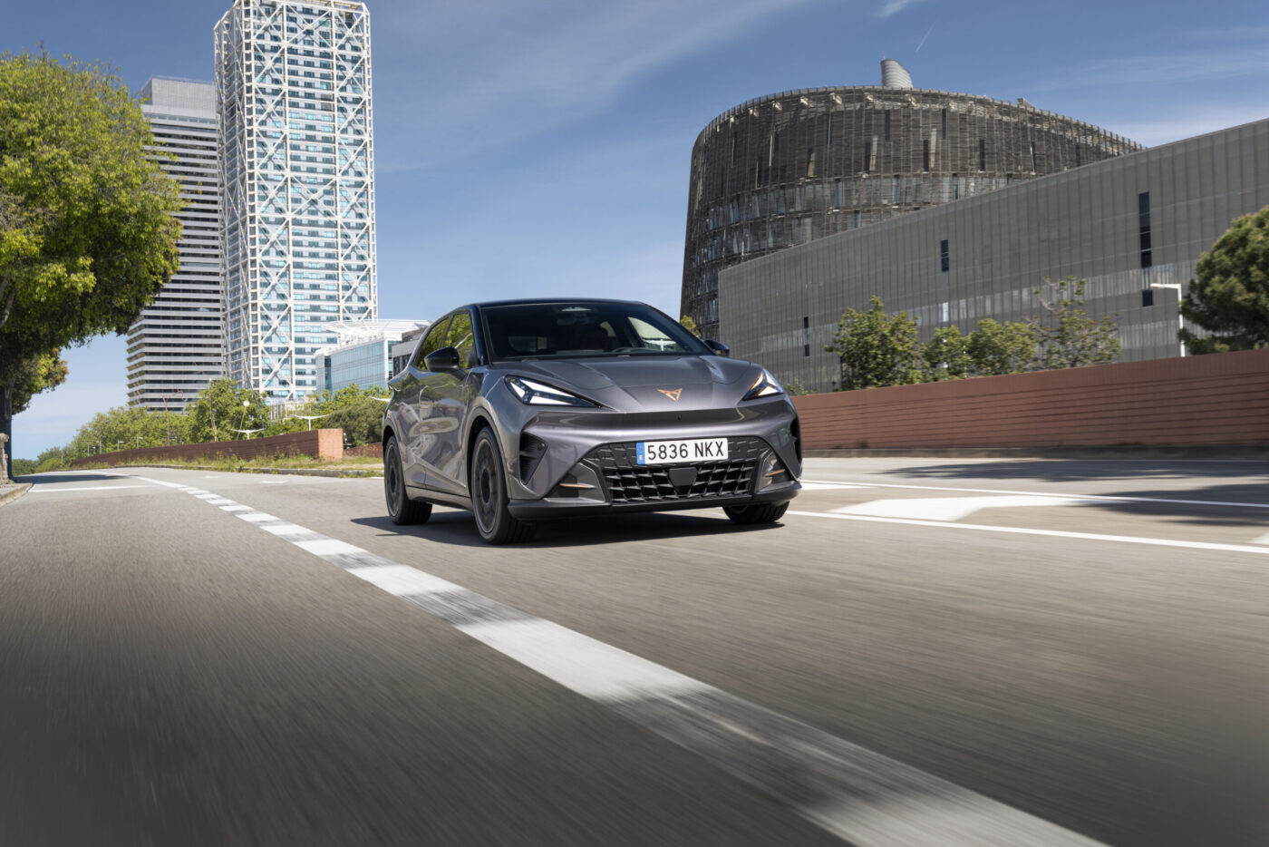 CUPRA Raval Plus in Grau fährt auf einer Stadtstraße, Frontansicht mit LED-Scheinwerfern
