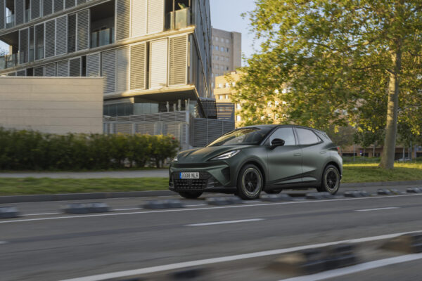 CUPRA Raval Plus in mattem Olivgrün fährt durch eine baumgesäumte Stadtstraße