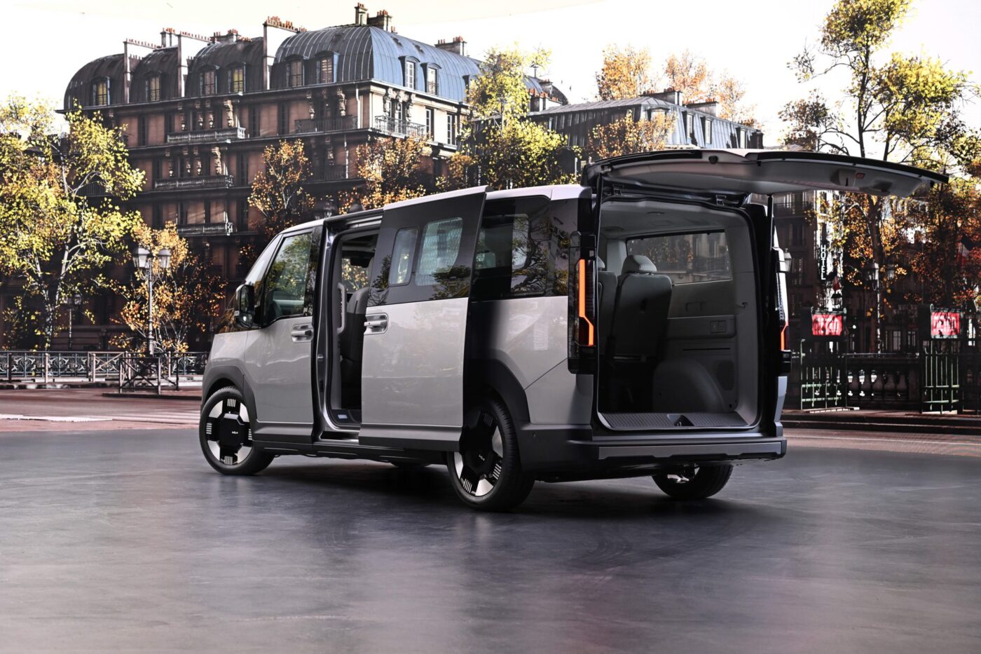 Kia PV7 Passenger von schräg hinten mit geöffneten Hecktüren in urbaner Umgebung