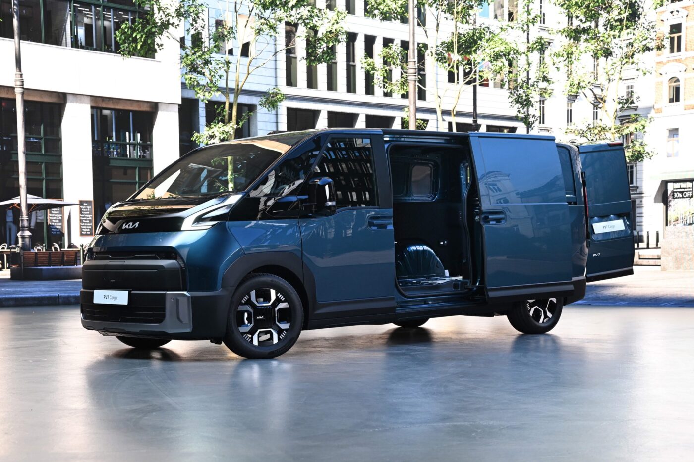 Kia PV7 Cargo in Blaugrün mit geöffneter Schiebetür, schräg von vorne links, auf Stadtplatz