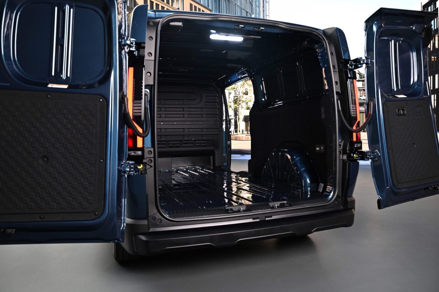 Leerer Laderaum des Kia PV7 Cargo mit geöffneten Hecktüren, Bodenschienen und LED-Beleuchtung