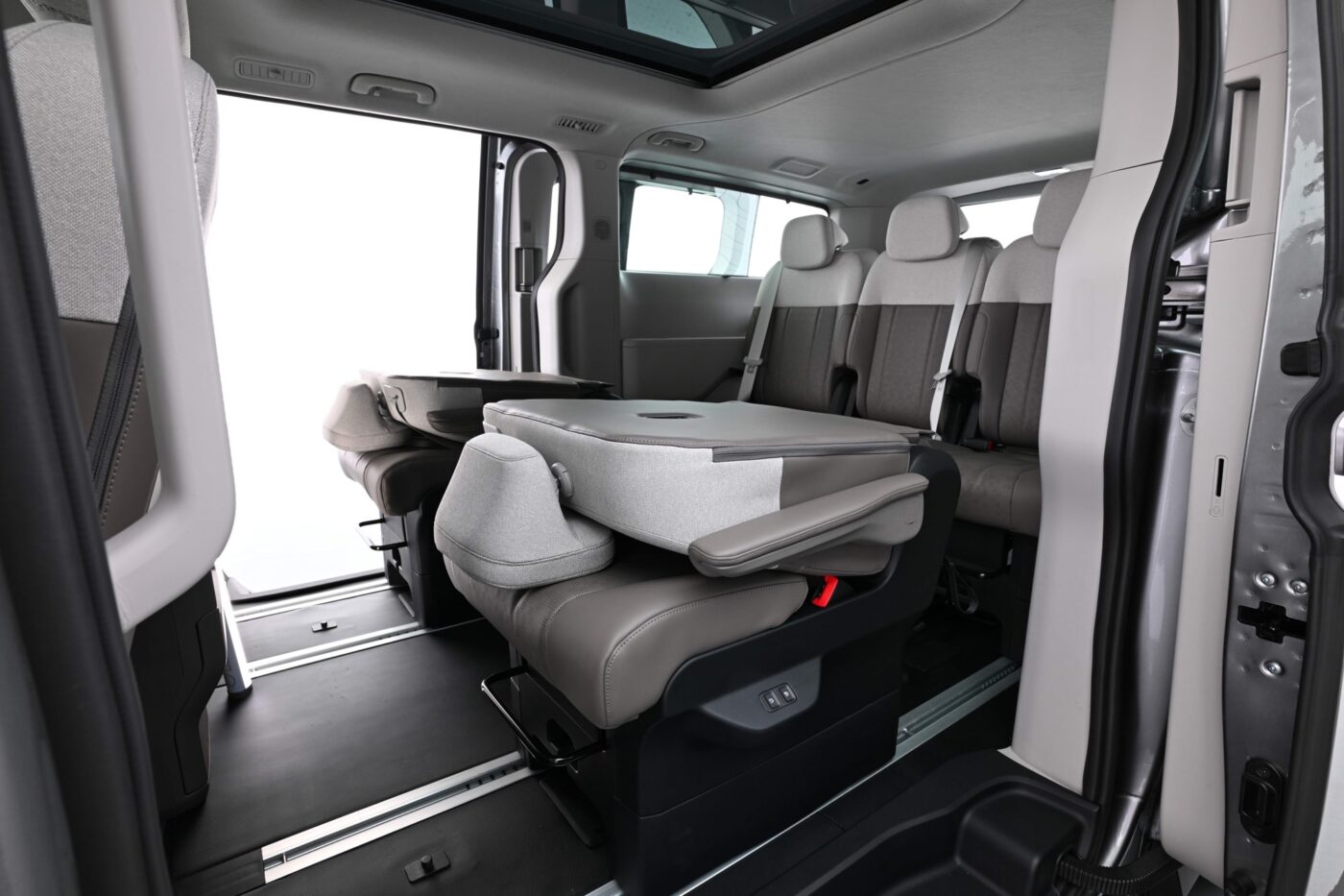 Kia PV7 Passenger: umgeklappter Mittelsitz als Tisch in der zweiten Reihe, dahinter drei weitere Sitze