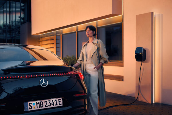 Frau lädt schwarzen Mercedes-Benz EQS an privater Wallbox zu Hause mit MB.CHARGE Home