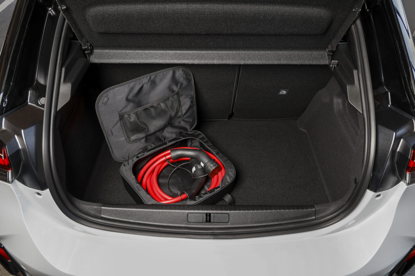 Kofferraum des Opel Corsa GSE mit aufgerolltem rotem Typ-2-Ladekabel in schwarzer Transporttasche
