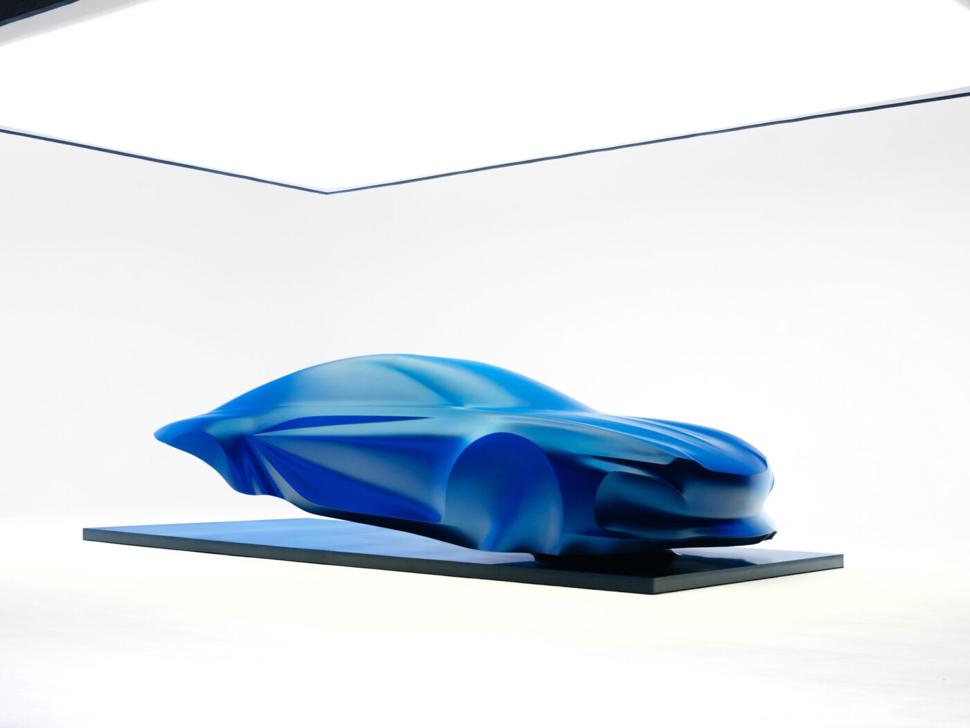 Alpine A110 der dritten Generation als blaue Designskulptur unter transparentem Schleier auf Podest
