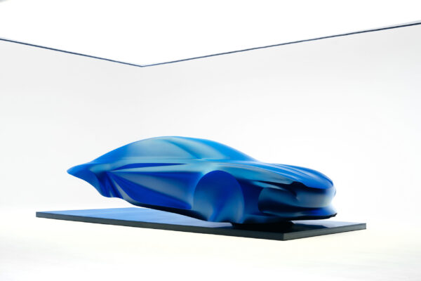 Alpine A110 der dritten Generation als blaue Designskulptur unter transparentem Schleier auf Podest