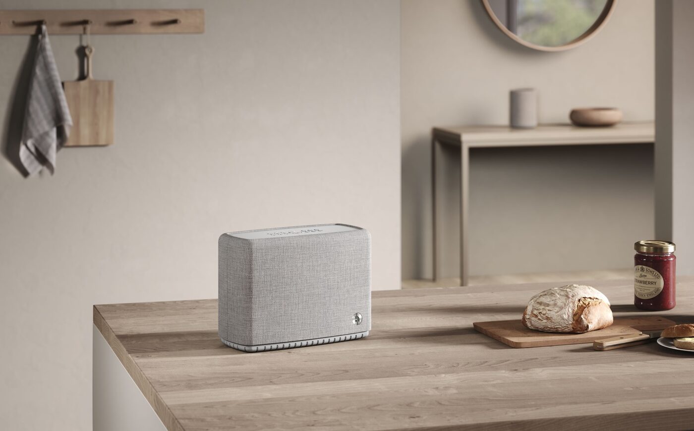 Audio Pro Lautsprecher mit grauem Stoffbezug auf Holztheke in minimalistischer Küche