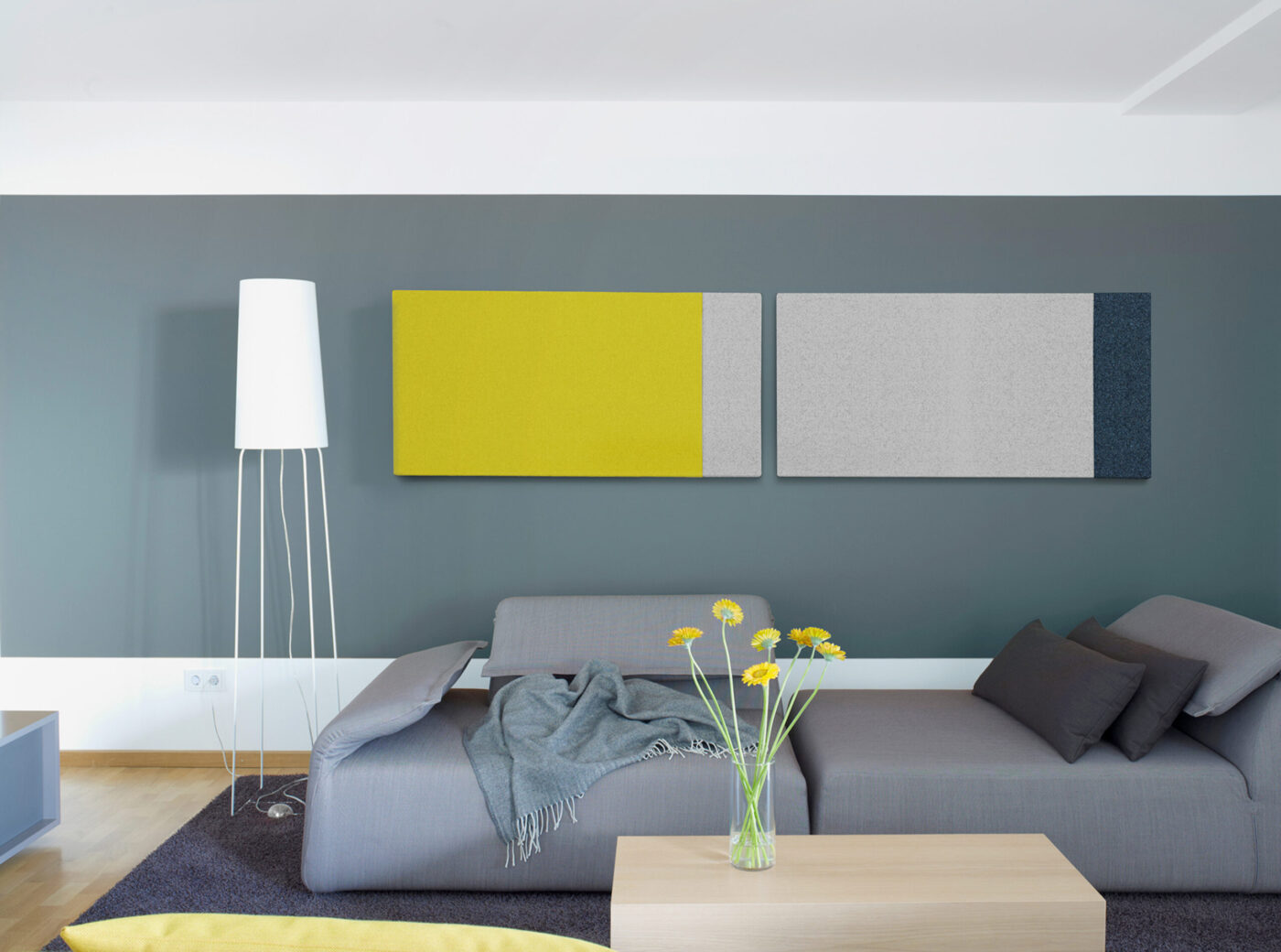 Création-Baumann-Akustikpaneele in Gelb, Grau und Dunkelblau an grau-blauer Wohnzimmerwand