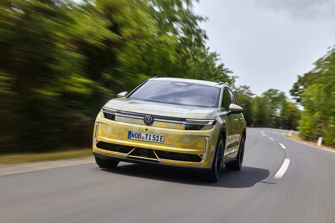 VW ID. Tiguan Prototyp mit gelbem Tarnmuster fährt auf Landstraße – Frontansicht