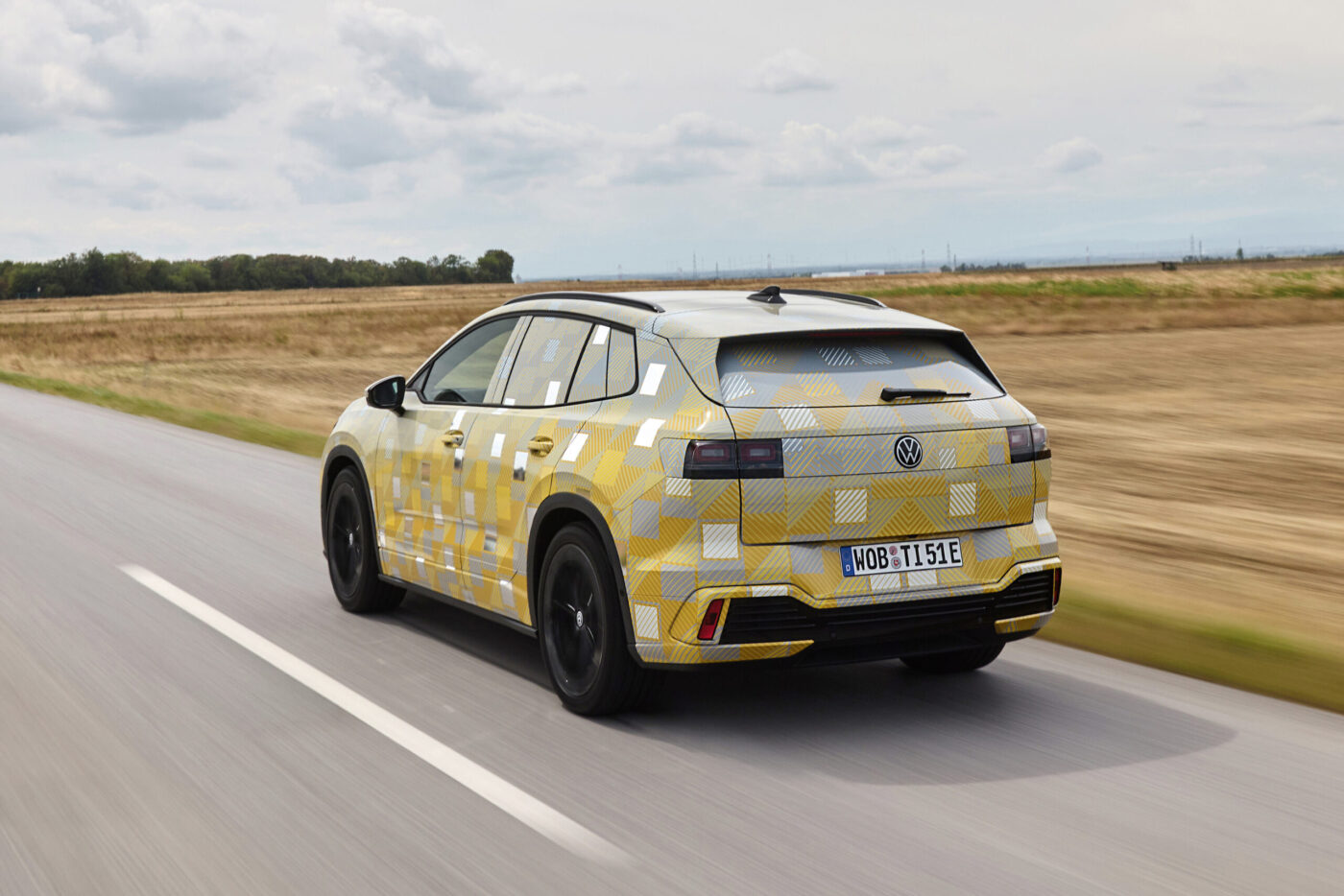 VW ID. Tiguan Prototyp mit Tarnfolie in Gelb-Weiß auf Landstraße, Heckansicht