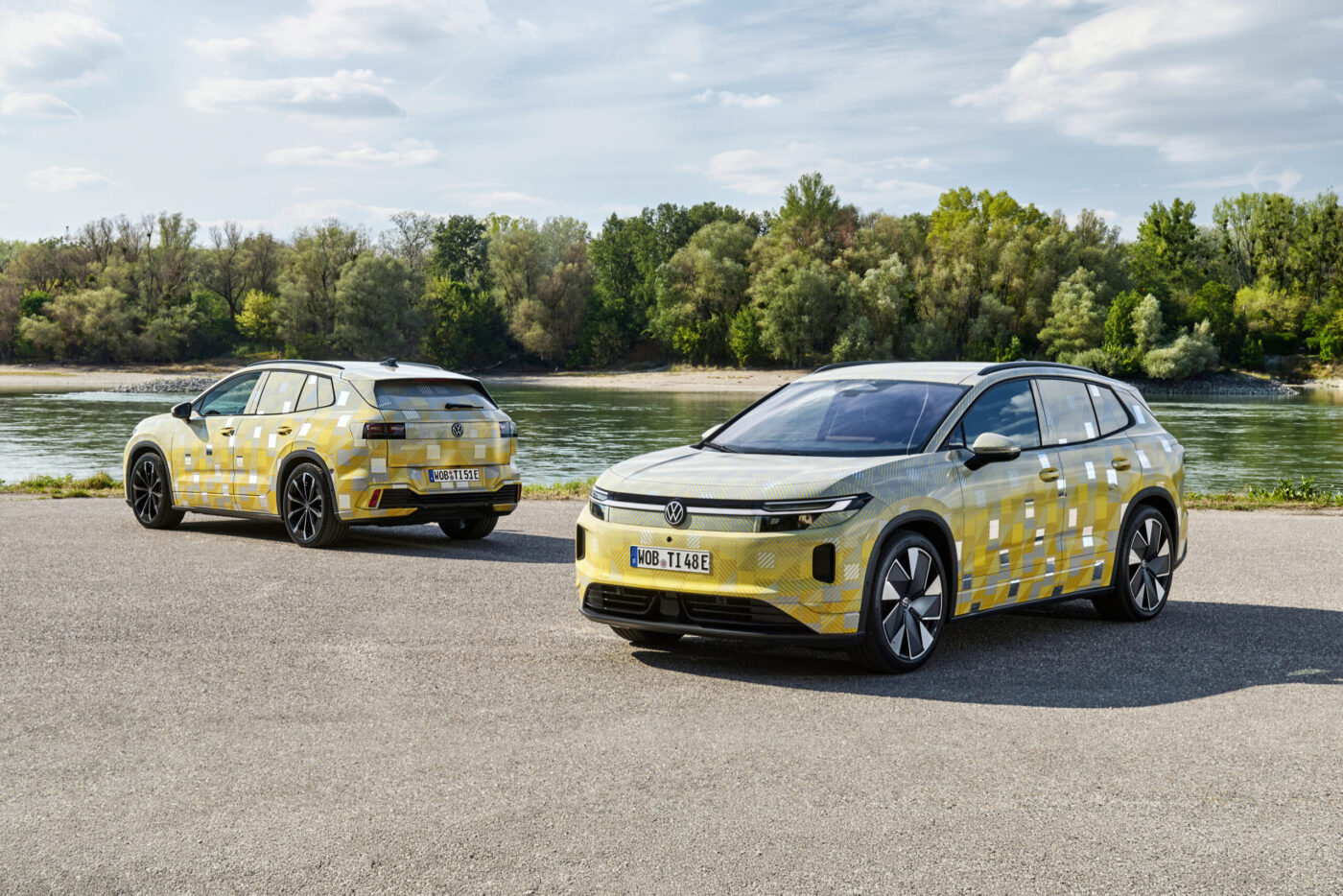 Zwei VW ID. Tiguan Prototypen mit gelbem Tarnmuster vor Flusslandschaft