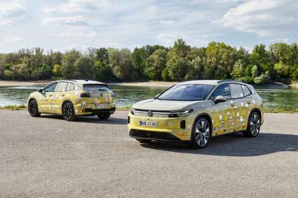 Zwei VW ID. Tiguan Prototypen mit gelbem Tarnmuster vor Flusslandschaft