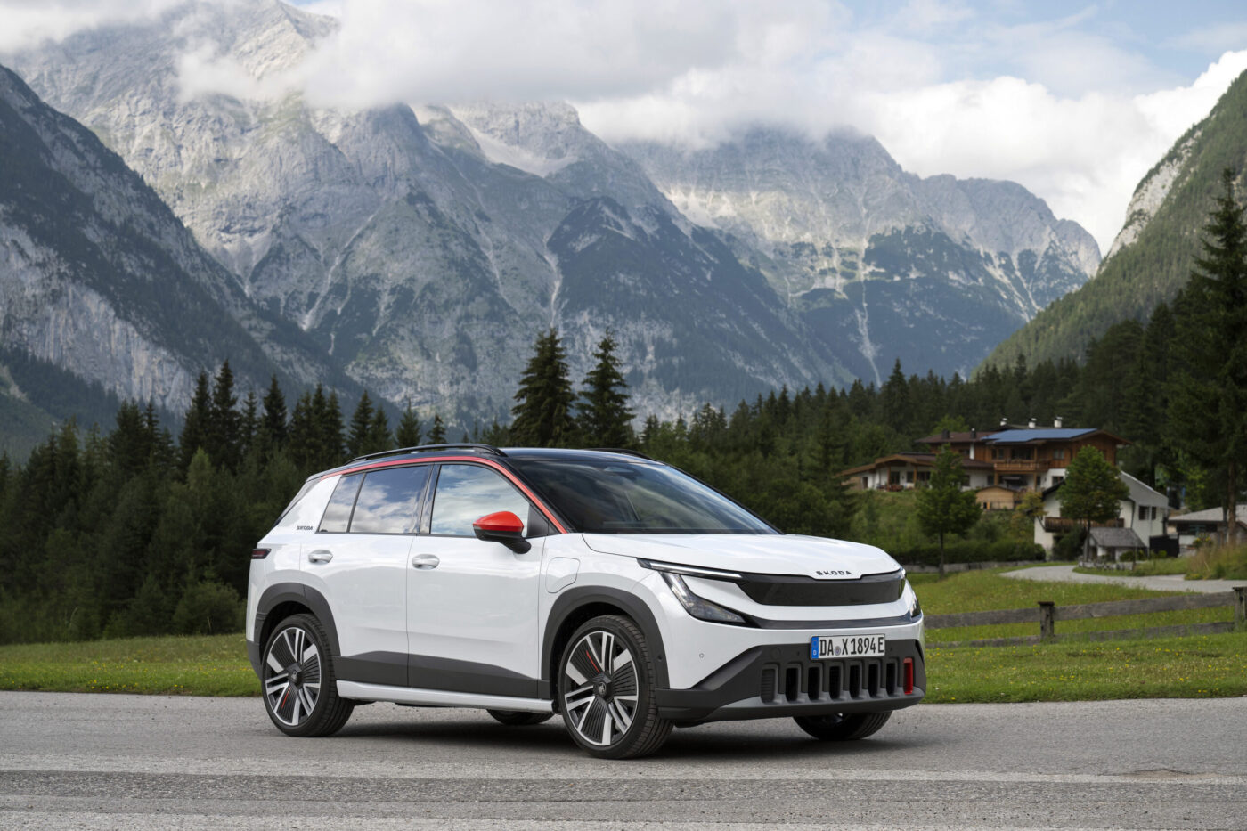 Škoda Epiq in Weiß mit roten Akzenten vor alpiner Bergkulisse, Dreiviertelansicht
