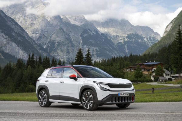 Škoda Epiq in Weiß mit roten Akzenten vor alpiner Bergkulisse, Dreiviertelansicht