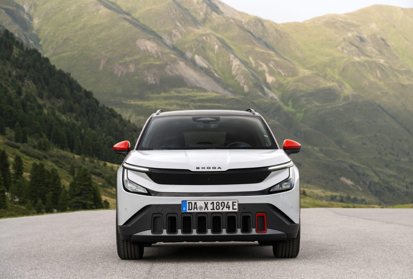 Škoda Epiq in Weiß, Frontansicht vor Bergpanorama, rote Außenspiegel, deutsches E-Kennzeichen